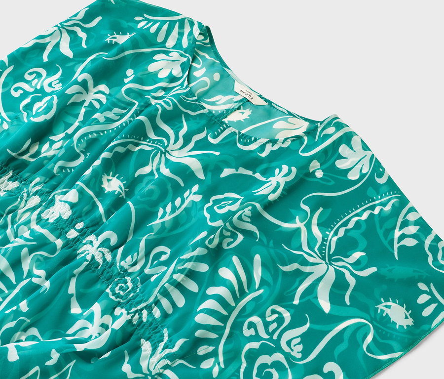 Gros plan d'un haut turquoise avec un motif blanc.