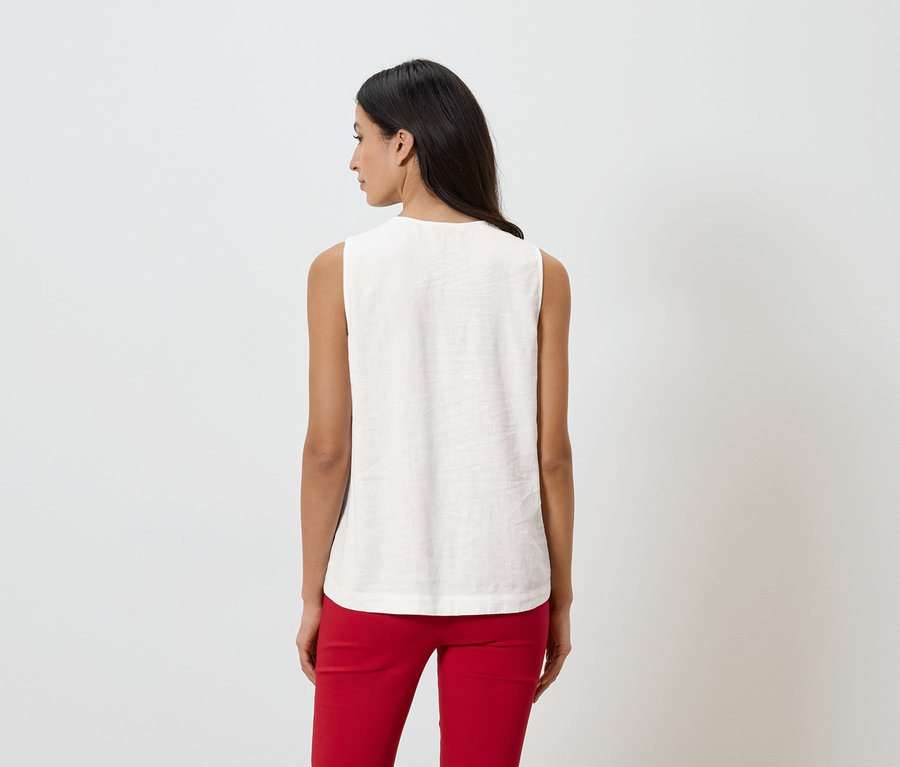 Femme de dos portant un haut sans manches et un pantalon rouge sur fond blanc.