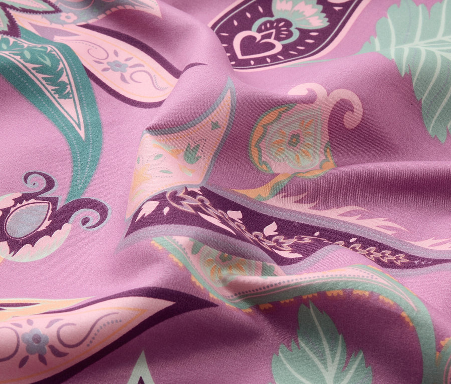 Gros plan d'un tissu violet avec un motif cachemire coloré.