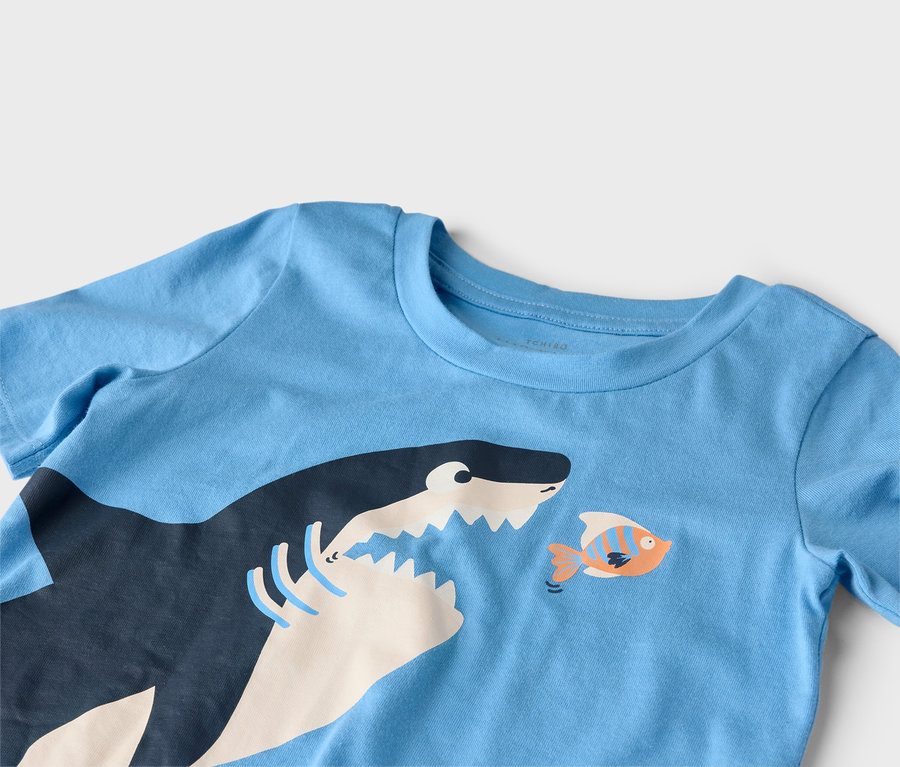 T-shirt bleu avec un motif de requin et de poisson.