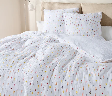 Gros plan d'un lit avec des draps blancs à motifs floraux et des oreillers.
