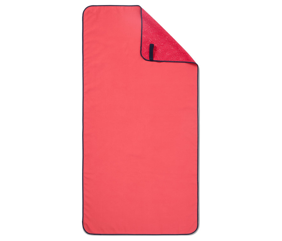 Une serviette corail avec une bordure bleu marine est pliée sur une surface plane.