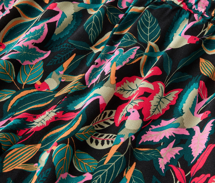 Gros plan d'un tissu noir avec un motif de feuilles et d'oiseaux de différentes couleurs.