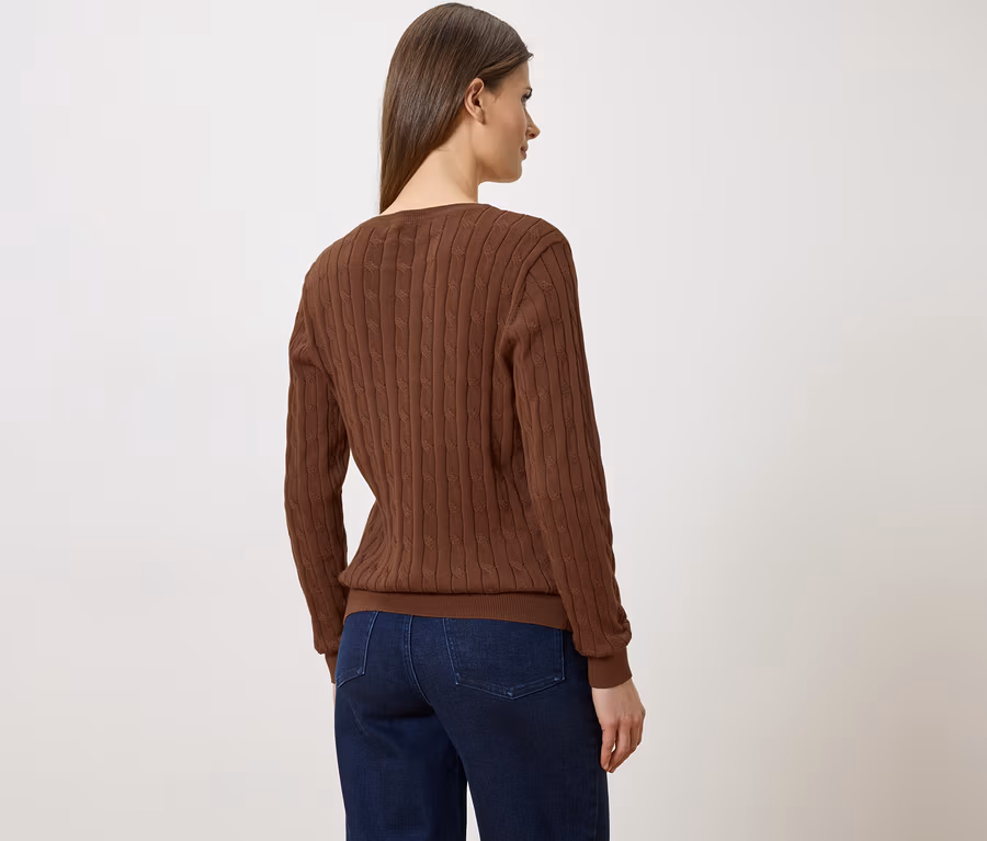 Vue arrière d'une femme avec une tresse brune, portant un pull en maille torsadée marron et un jean bleu sur fond blanc.