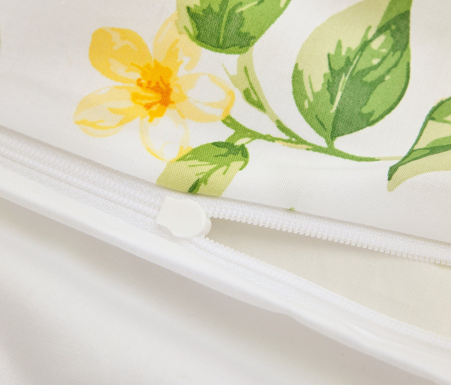 Gros plan d'un coussin blanc partiellement ouvert avec fermeture éclair et motif floral jaune.