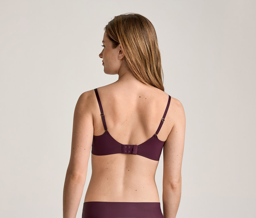 Vue arrière d'une femme aux longs cheveux bruns portant un soutien-gorge et une culotte bordeaux.