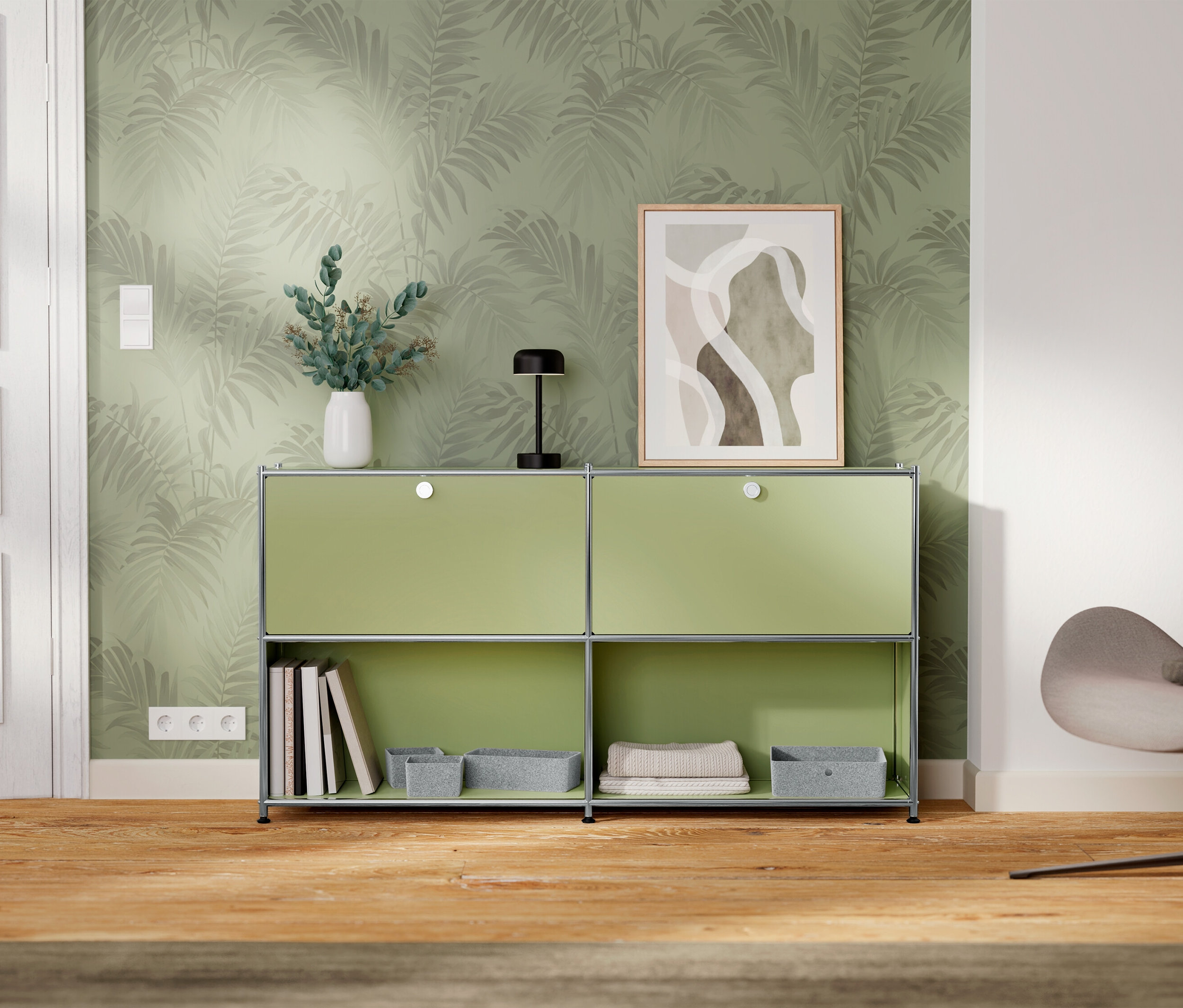 Une armoire verte à deux compartiments se trouve contre un mur avec du papier peint à motifs de feuilles.