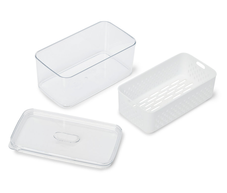 Un récipient transparent, un récipient perforé blanc et un couvercle transparent reposent sur une surface blanche.