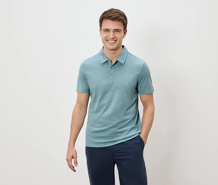 Homme souriant portant un polo bleu et un pantalon bleu marine.