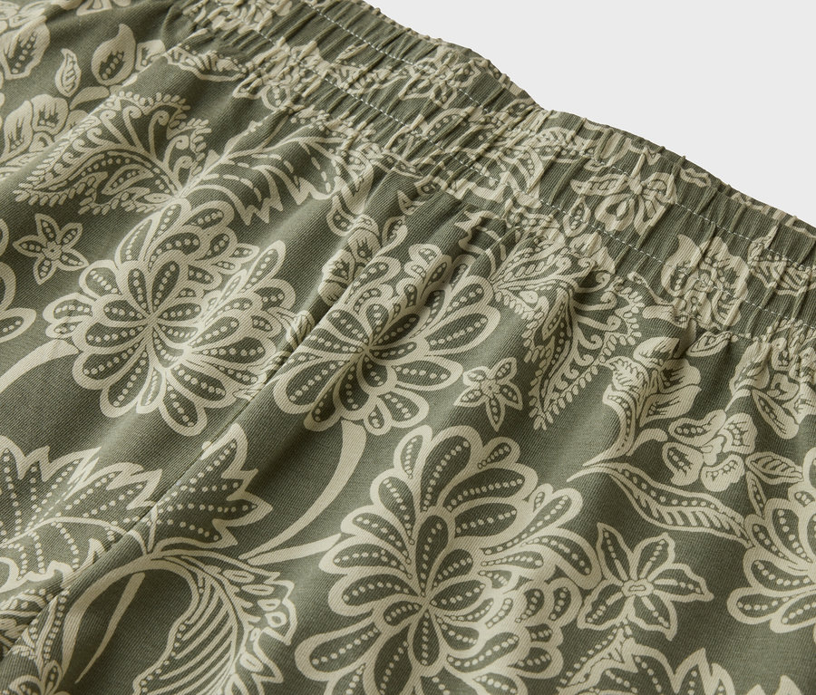 Gros plan sur la ceinture élastique d'un pantalon à motif floral vert et beige.