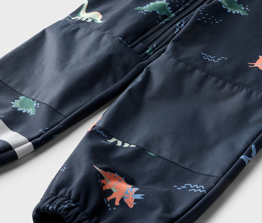 Gros plan d'un pantalon bleu marine à motif dinosaure, avec une fermeture éclair en haut et une bande blanche sur la jambe.
