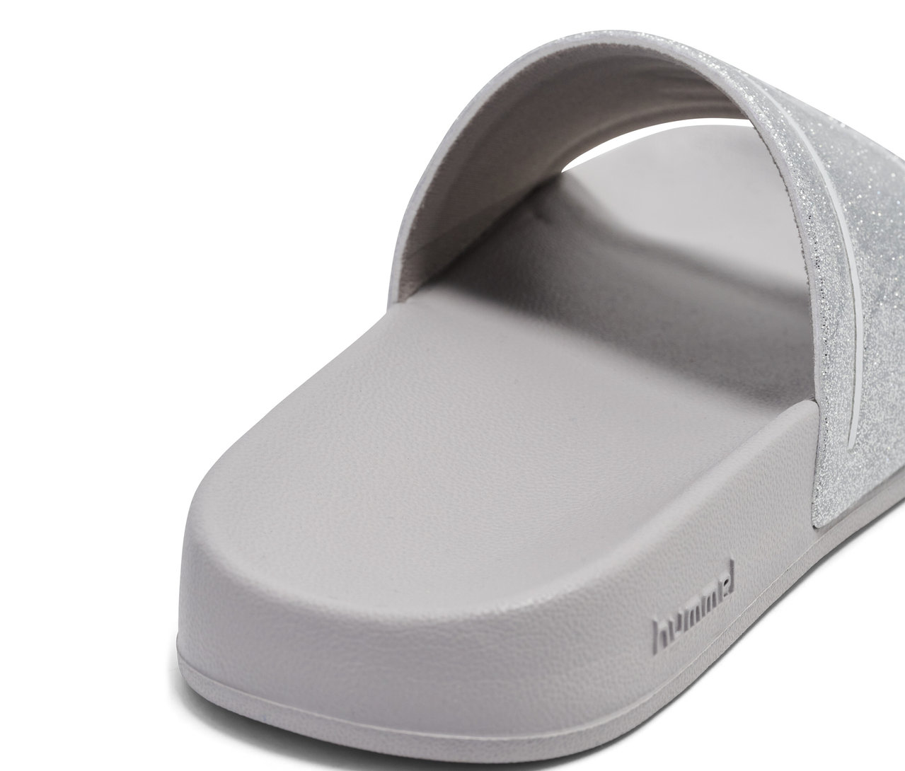 Gros plan d'une unique tong de bain hummel® Pool Slide GlitterJR grise avec une bride pailletée.
