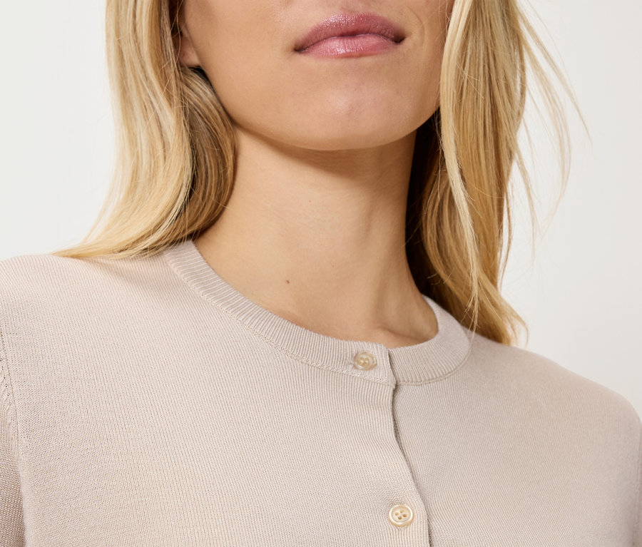Gros plan d'une femme blonde portant un cardigan beige.