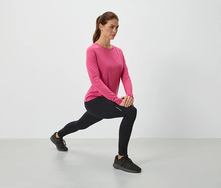 Femme en haut rose et leggings noirs en train de s'étirer.