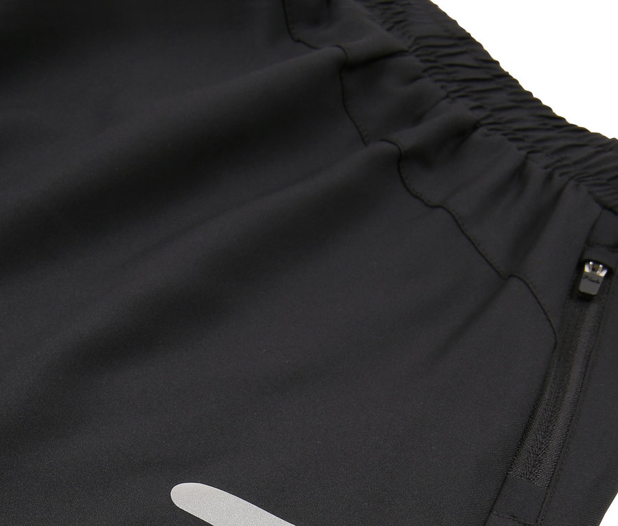 Gros plan sur un short noir avec taille élastique, poche zippée et bandes réfléchissantes.