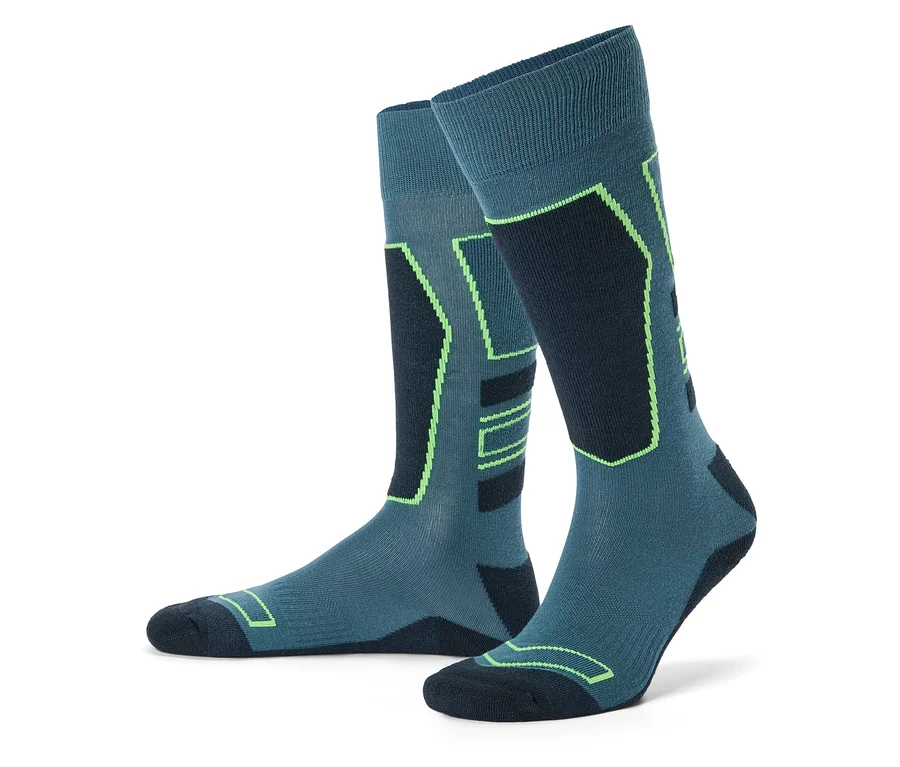 Une paire de chaussettes de ski montantes bleu sarcelle et bleu foncé avec des accents géométriques vert fluo, posées droites sur un fond blanc.
