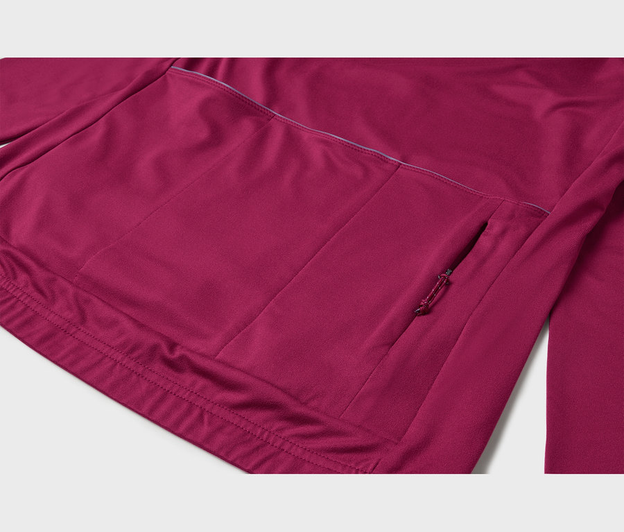 Vue rapprochée du dos d'un haut de sport magenta à manches longues, montrant trois poches ouvertes et une poche zippée avec tirette sur le côté droit. Une bande réfléchissante passe au-dessus des poches.