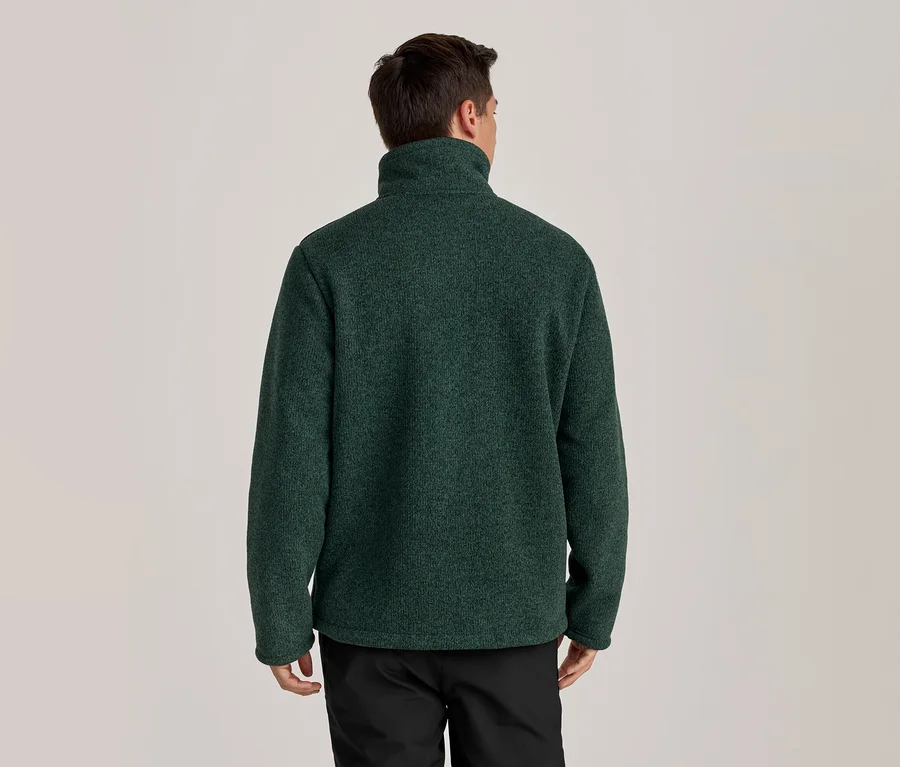 Homme de dos portant une veste polaire vert foncé à col montant et un pantalon noir.