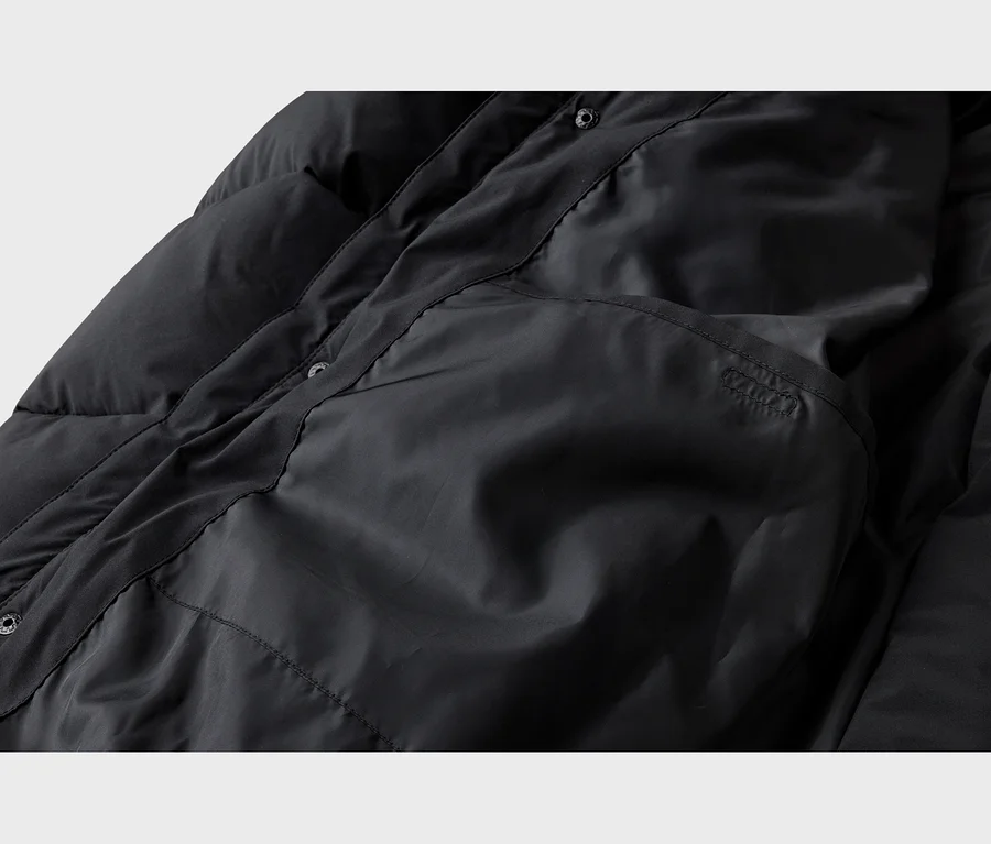 Intérieur d'une doudoune noire matelassée avec doublure, poche intérieure et boutons-pression.