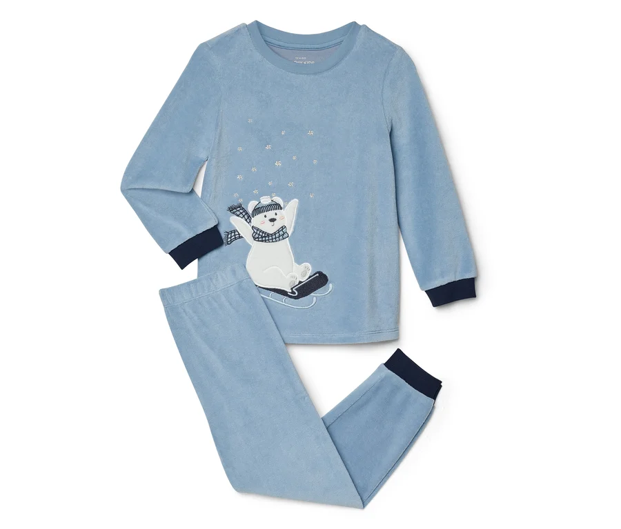 Pyjama en velours bleu clair avec un haut à manches longues et un pantalon long. Le haut présente un ours polaire blanc brodé sur une luge noire, portant un bonnet et une écharpe rayés, entouré de flocons de neige argentés. Les poignets et les chevilles sont bleu foncé.