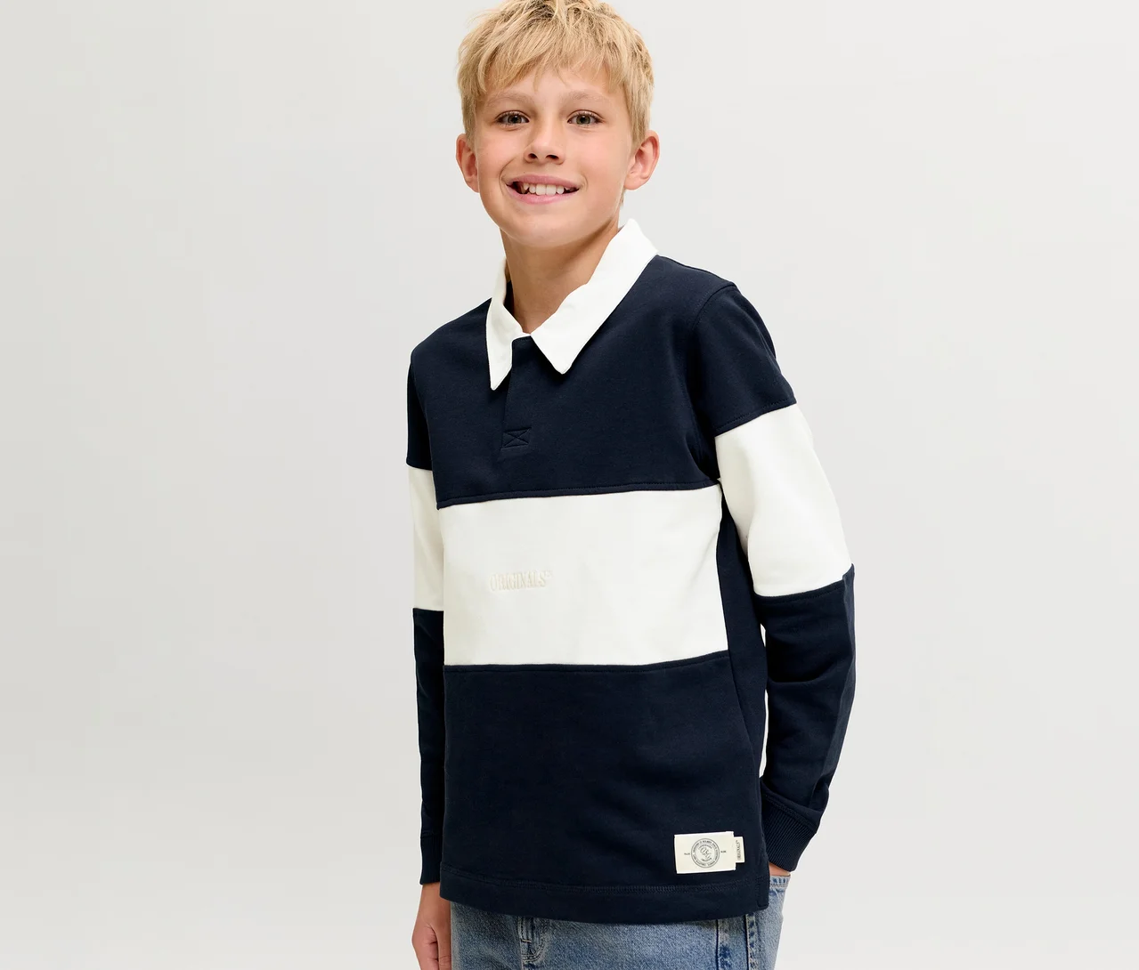 Garçon blond souriant portant un pull polo Jack&Jones rayé bleu marine et blanc avec un col blanc.