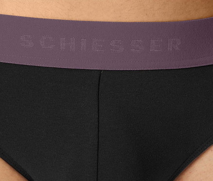 Gros plan sur un slip noir pour homme avec une ceinture violette de la marque Schiesser.