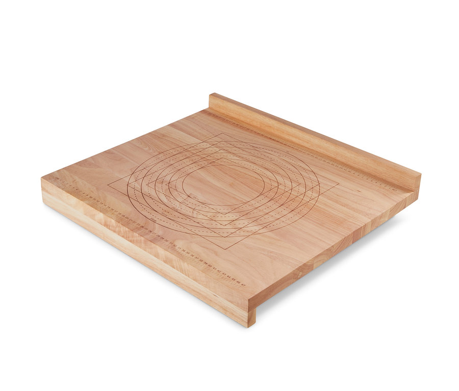 Une planche à pâtisserie en bois avec des cercles et des rectangles marqués pour travailler la pâte.
