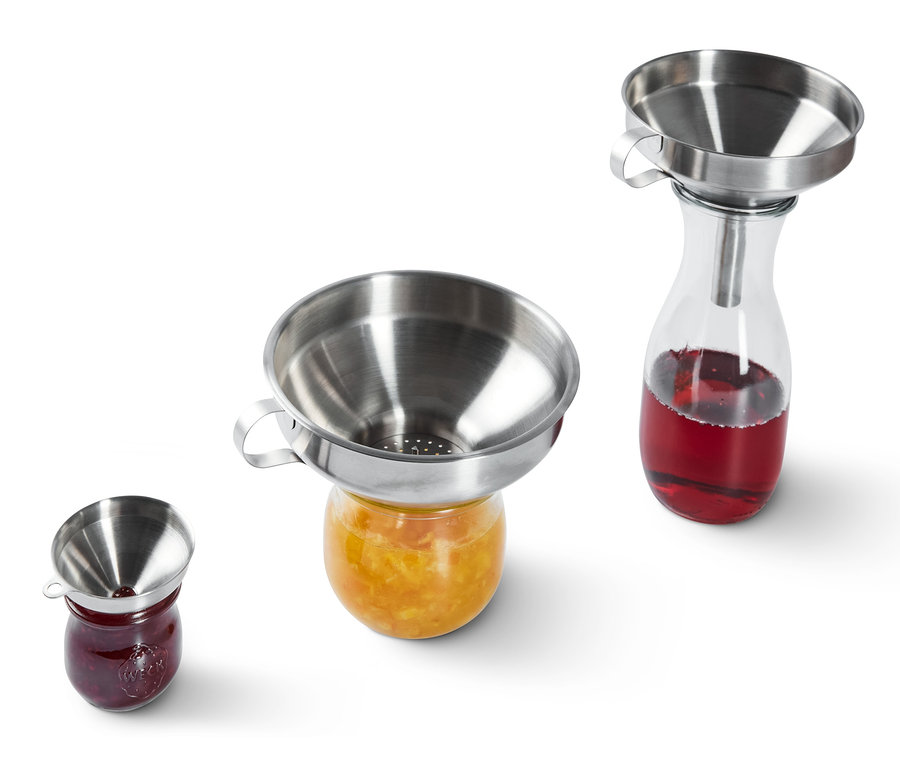 Des entonnoirs en acier inoxydable reposent sur des pots de confiture.