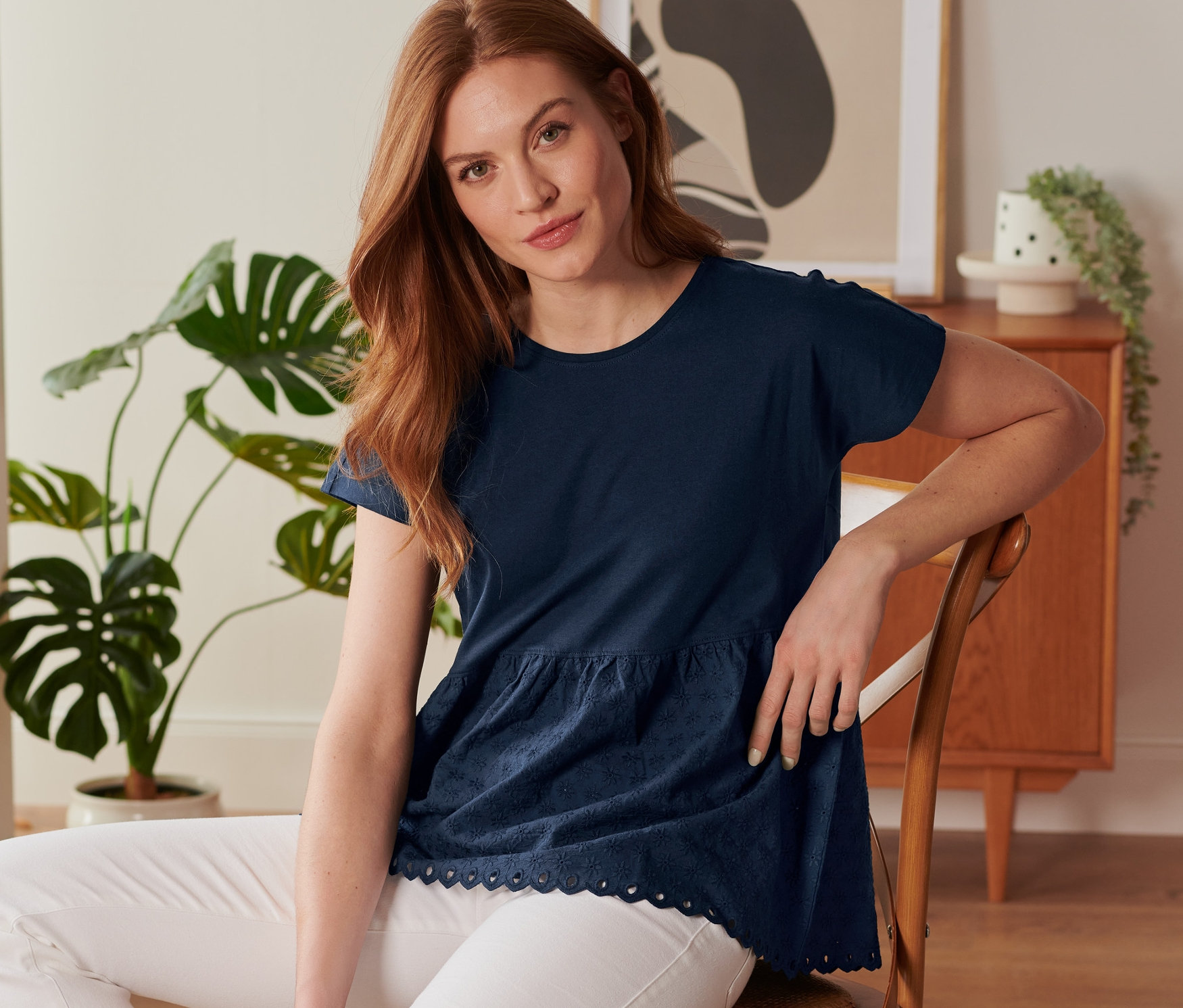 Femme assise sur une chaise portant un t-shirt bimatière à broderie bleu foncé.