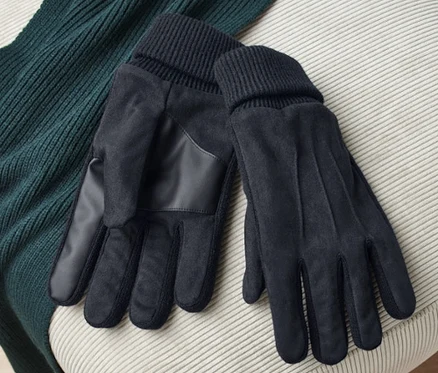 Sur un tabouret beige reposent une paire de gants noirs et un pull vert.