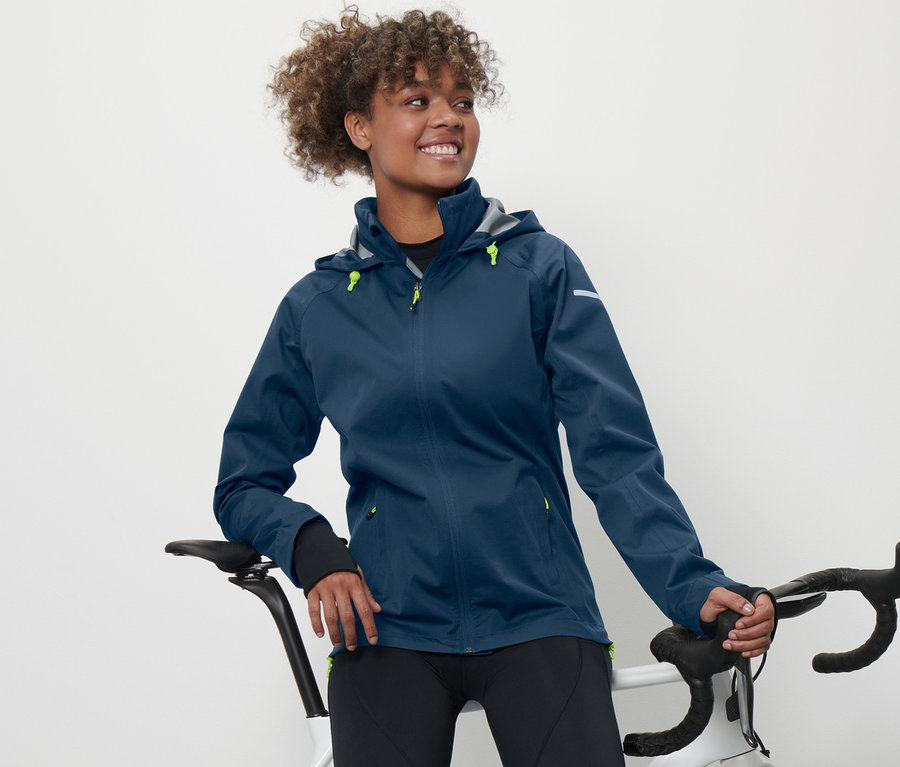 Une femme appuyée sur un vélo porte une veste imperméable cycliste.