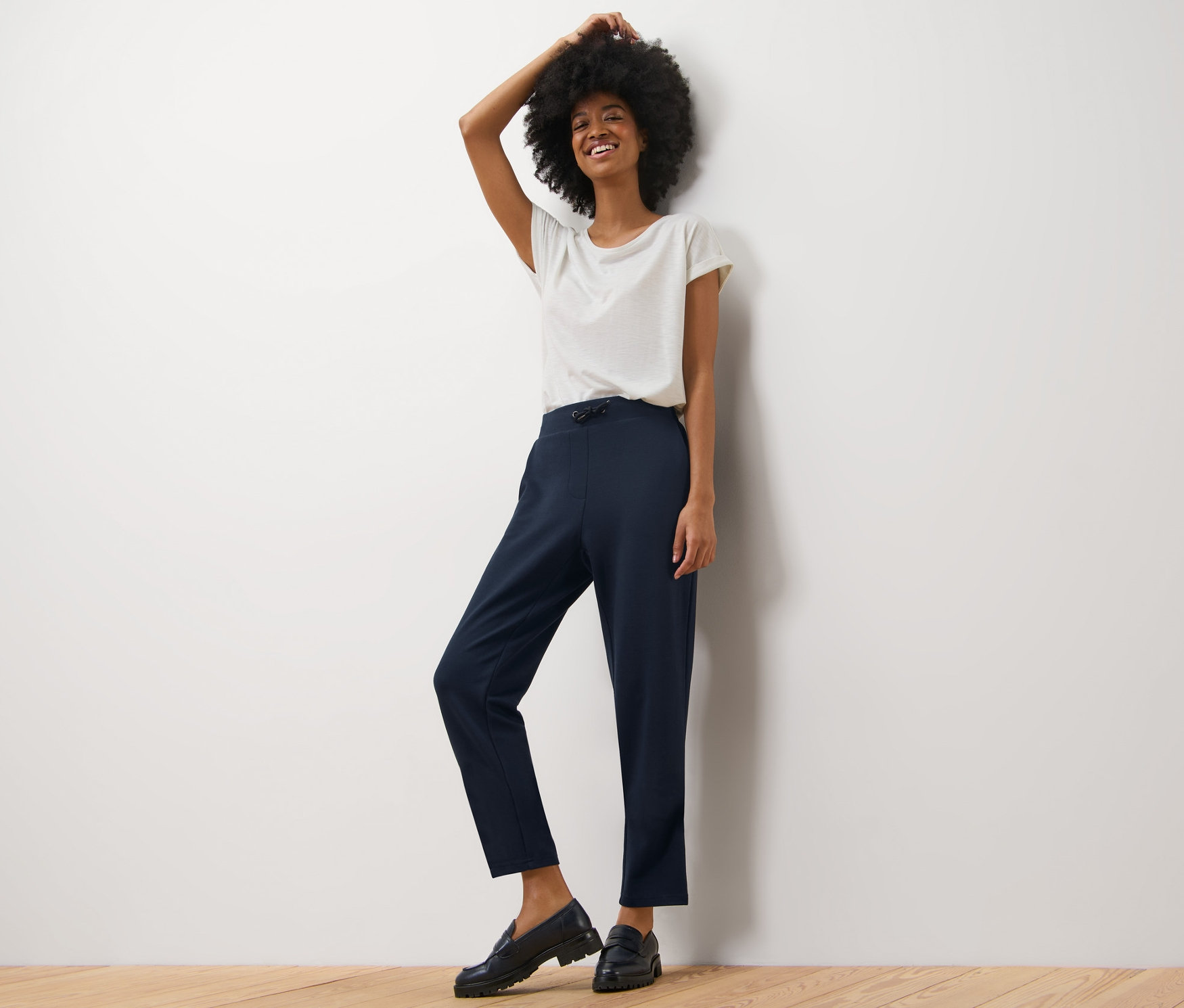 Femme posant en pantalon de jogging et t-shirt blanc.