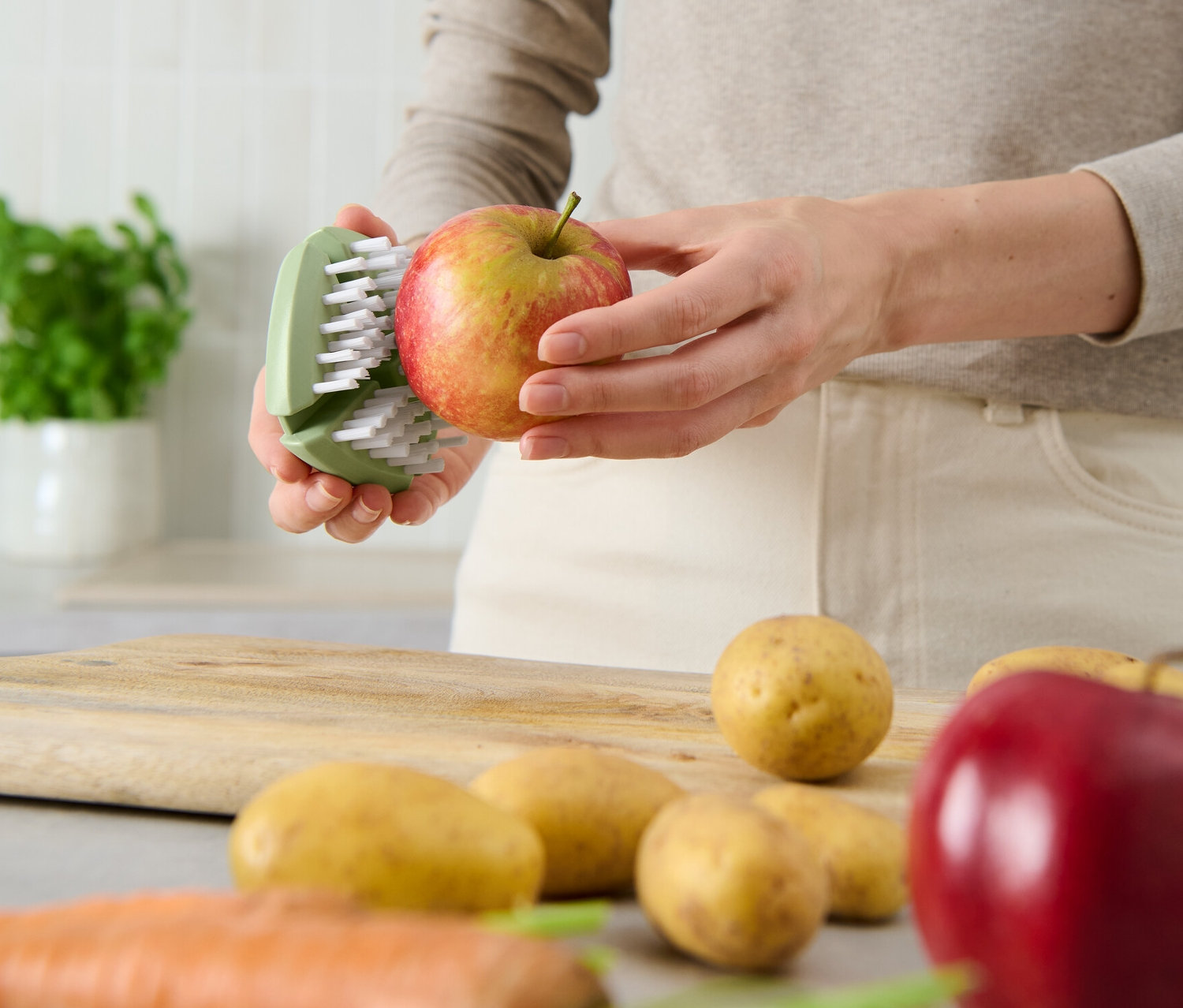 Femme nettoyant une pomme avec une brosse à légumes et à fruits flexible.