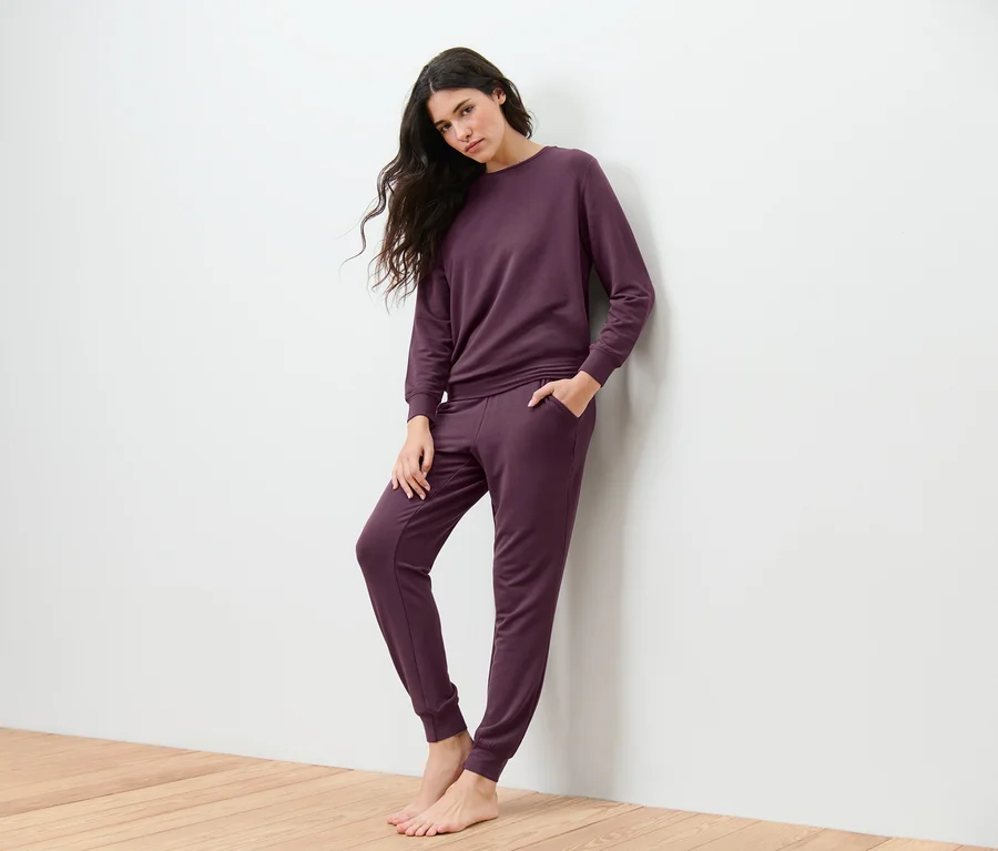 Femme appuyée contre un mur portant une tenue d’intérieur.