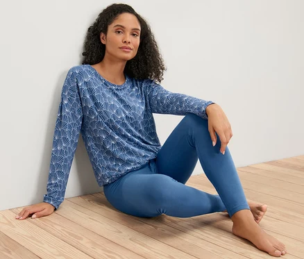 Femme assise par terre en pyjama avec legging.