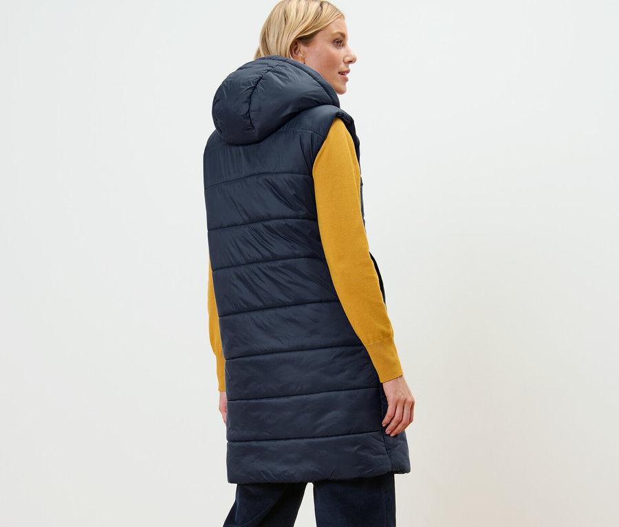 Femme vue de dos portant un long gilet sans manches matelassé avec capuche.