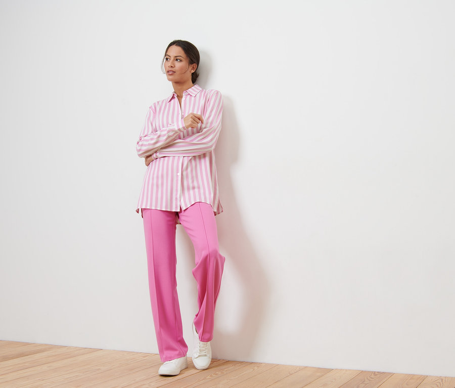 Femme posant en pantalon rose et blouse rayée.
