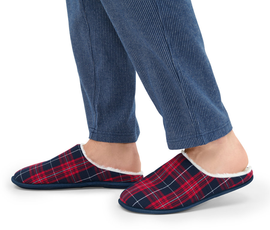 Pieds portant un pantalon bleu rayé et des chaussons à carreaux rouges et bleus.
