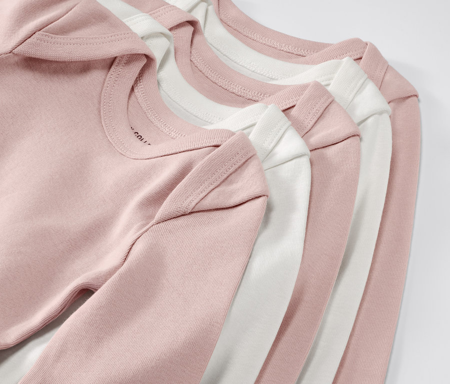 Gros plan sur cinq bodies roses et blancs évolutifs pour bébé. 5 bodys évolutifs pour bébé, roses.