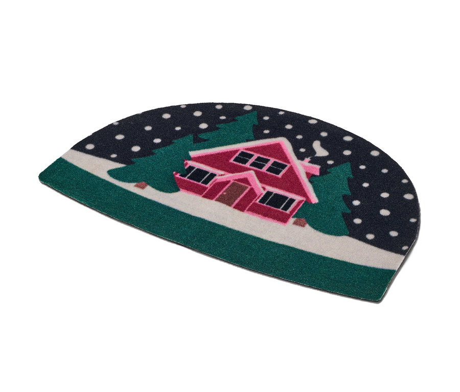 Paillasson avec un motif de maison enneigée entre des arbres.