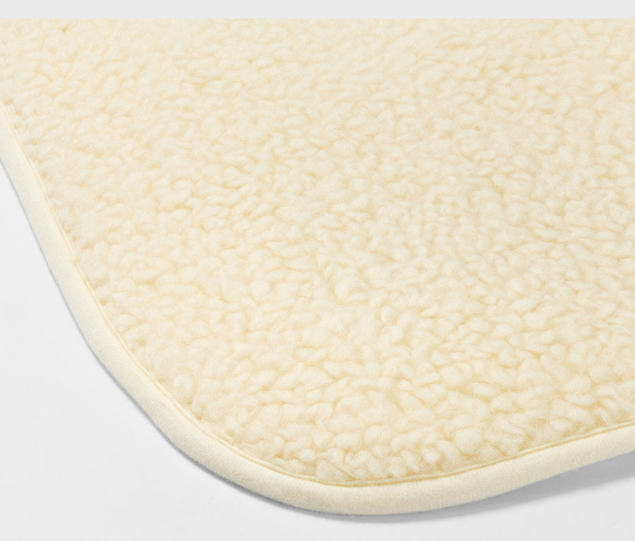 Détail d'un coin du tapis de yoga beige avec laine vierge.