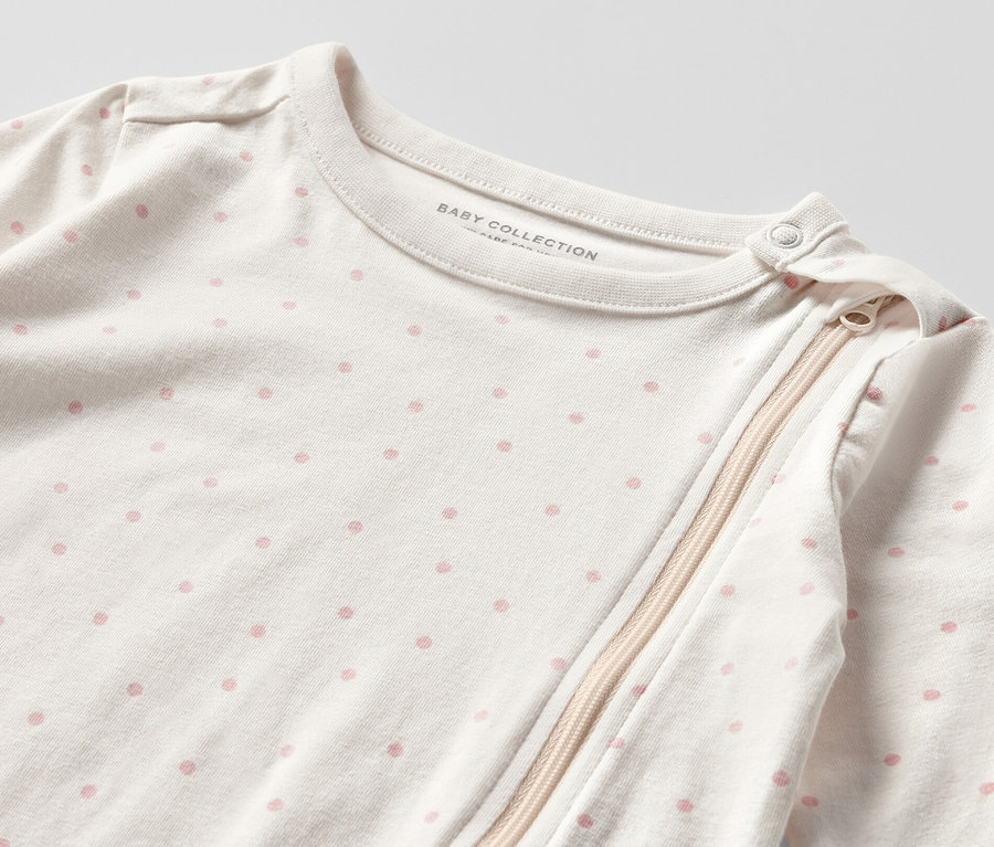 Gros plan sur un pyjama de bébé blanc à pois roses avec fermeture éclair. 3 pyjamas pour bébé, princesse.