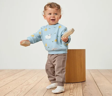 Un jeune enfant tient des blocs de bois, vêtu d'un ensemble en sweat pour bébé avec intérieur gratté.