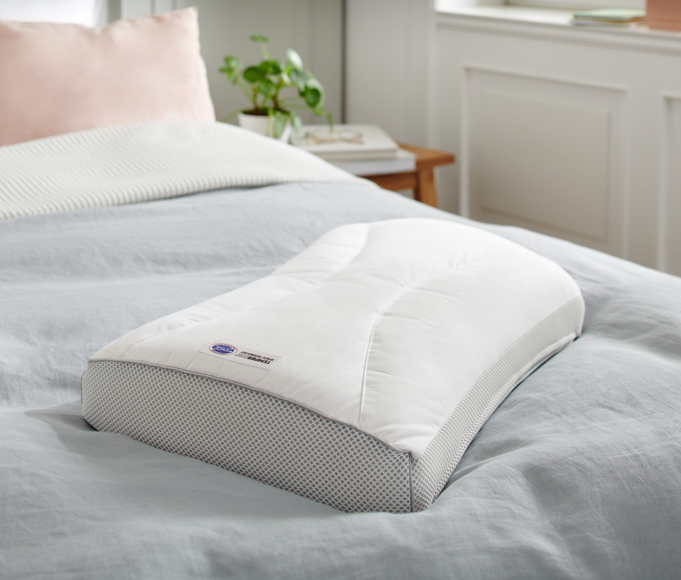 Un coussin Temprakon X-Zone est posé sur un lit avec un couvre-lit bleu.