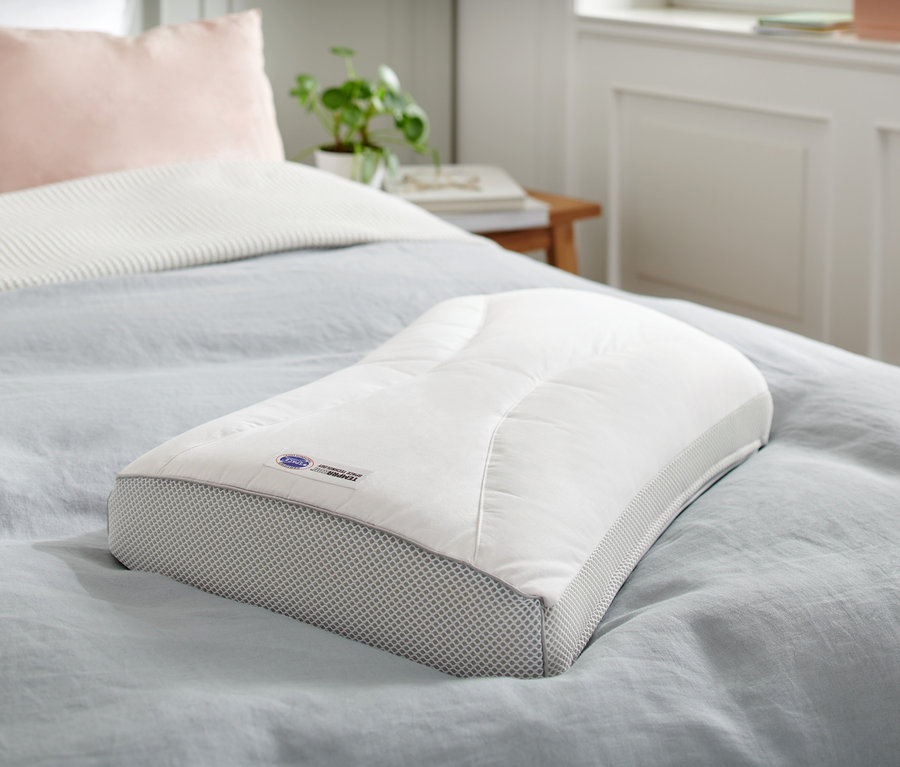 Un coussin Temprakon X-Zone est posé sur un lit avec un couvre-lit bleu.