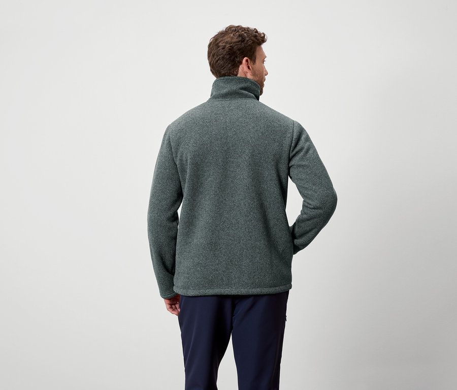 Un homme vu de dos porte une polaire gris-vert et un pantalon bleu marine.