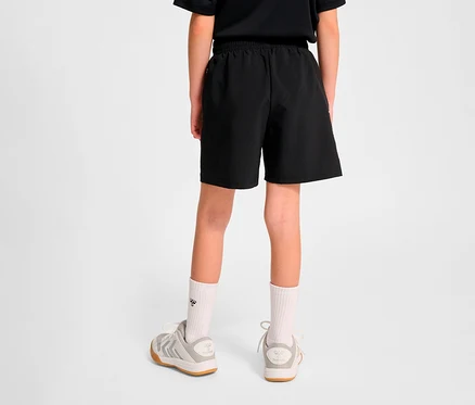 Vue arrière d'un enfant portant un short d'entraînement HUMMEL HMLJR Pulse noir et des baskets.