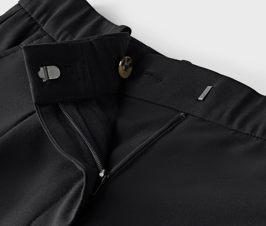 Gros plan d'un pantalon en tissu noir avec fermeture éclair et bouton.