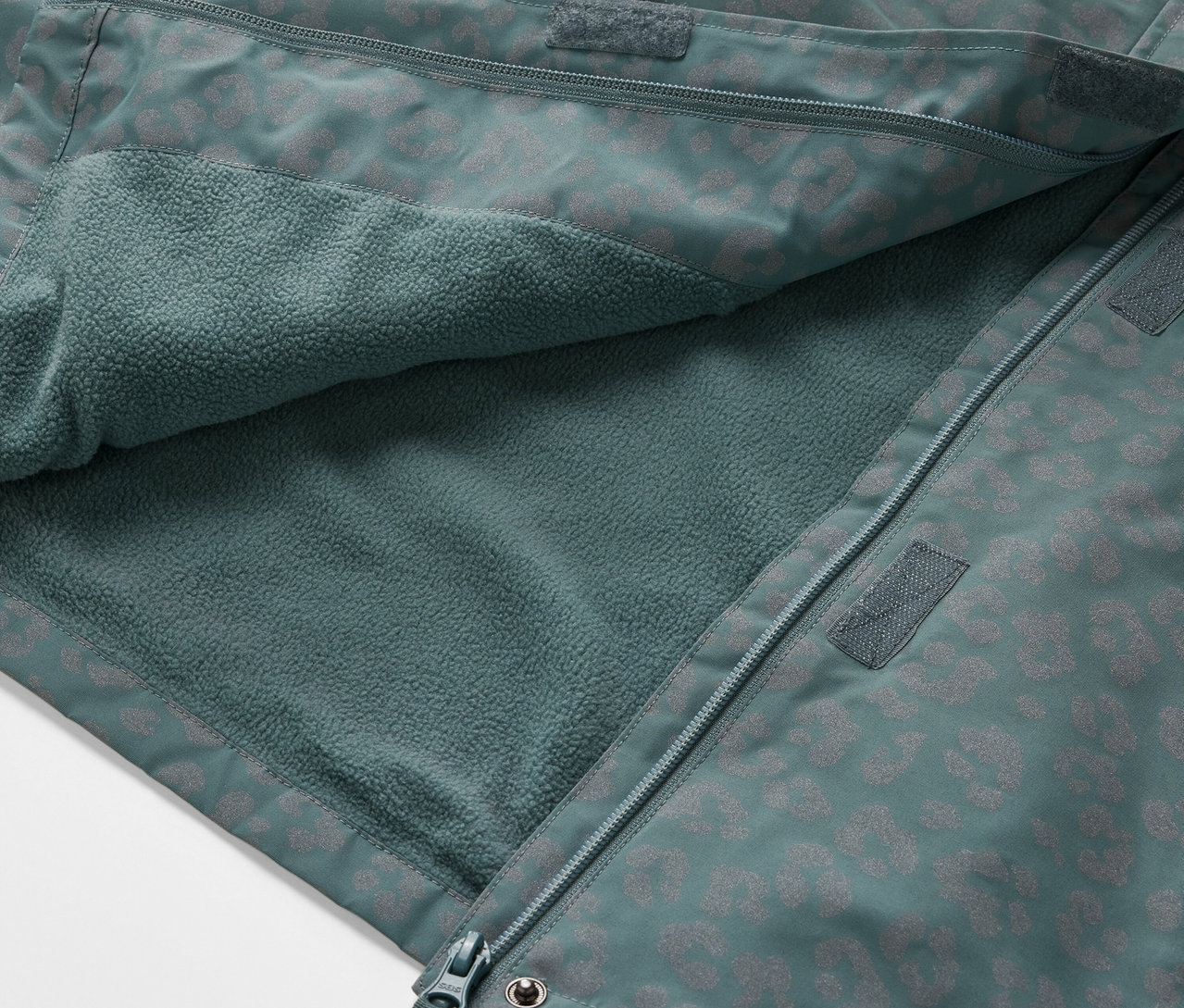 Gros plan sur une veste de pluie thermique pour enfant avec des éléments réfléchissants, ouverte pour montrer l'intérieur en polaire.