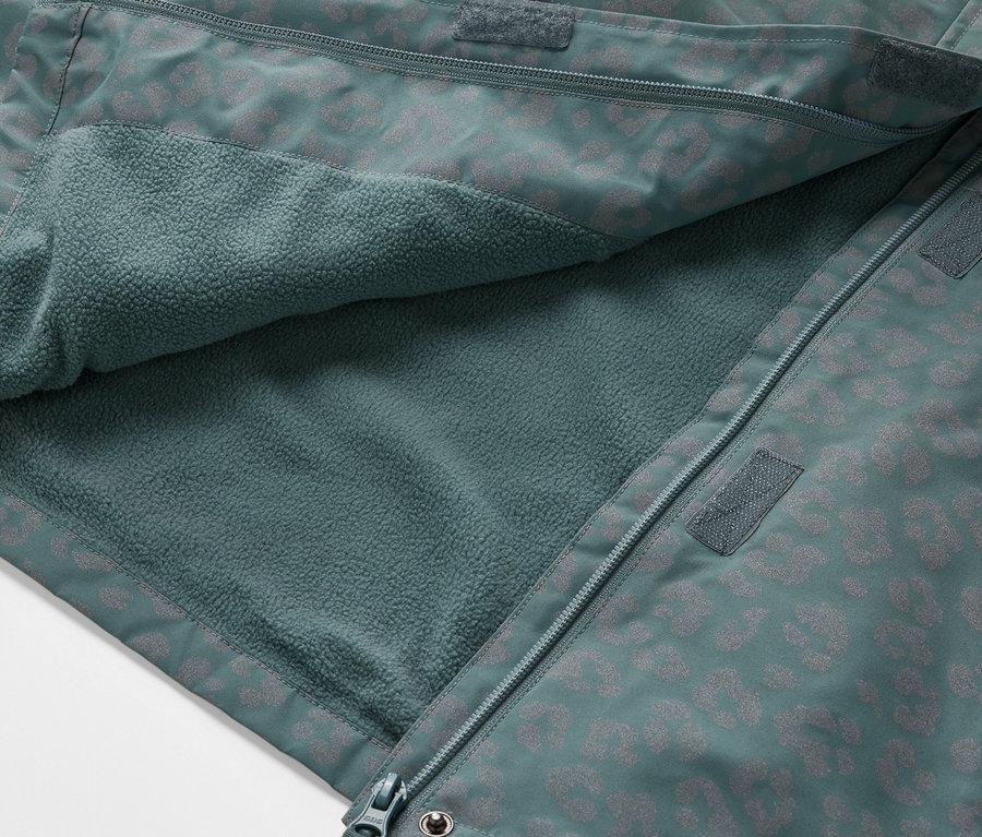 Gros plan sur une veste de pluie thermique pour enfant avec des éléments réfléchissants, ouverte pour montrer l'intérieur en polaire.